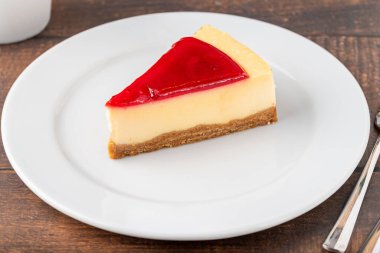 Lezzetli çilekli cheesecake, yanında kahve ve ahşap masa.