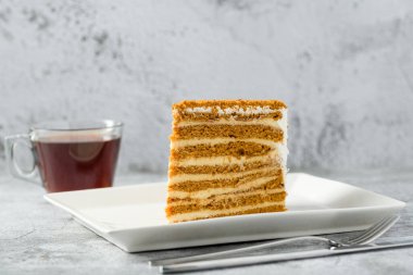 Taş zeminde beyaz porselen tabakta katmanlı ballı kek dilimi Medovik