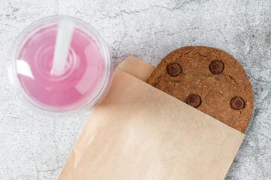 Kese kağıdına sarılı çikolatalı kurabiye ve yanında da içecek.