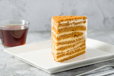 Taş zeminde beyaz porselen tabakta katmanlı ballı kek dilimi Medovik