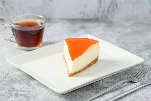 Pumpkin cheesecake on porcelain plate with tea on stone table