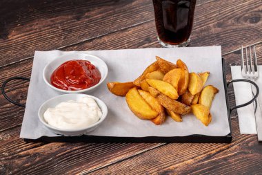 Ketçaplı patates dilimleri ve ahşap masada mayonez.