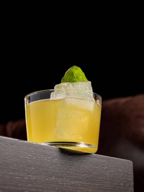 Ahşap masada koyu bir arka planda lüks bir kokteyl.