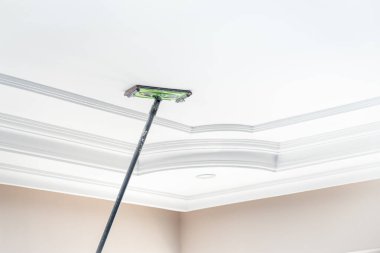 Usta boyanmak üzere odanın tavanına sıva yapıştırıyor.