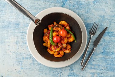 Shrimp casserole with tomatoes, garlic and peppers in black wok pan