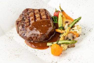 Beyaz porselen tabakta ızgara sebzeli Demi glace soslu ızgara sığır filetosu.