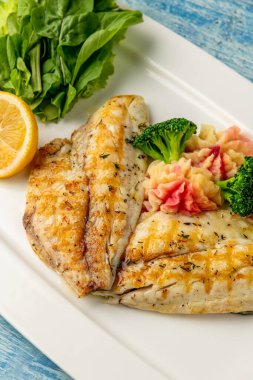 Ahşap masada sebze ve sebzeli ızgara deniz kepeği fileto.