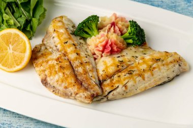 Ahşap masada sebze ve sebzeli ızgara deniz kepeği fileto.