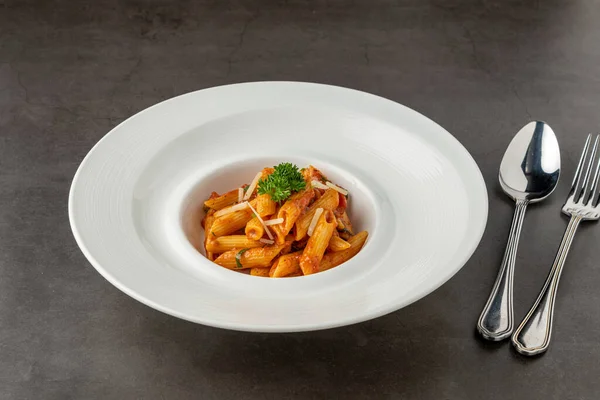 stock image Penne pasta in tomato sauce, tomatoes decorated with parsley on a wooden background