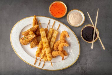 Siyah taş masadaki balık ve karidesli deniz ürünleri temposu.