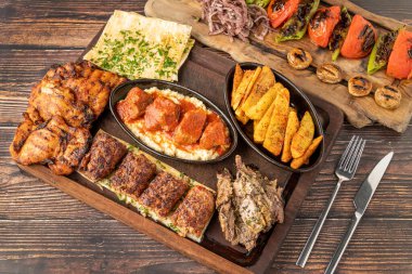 Ahşap masada adana kebabı, ızgara tavuk ve kuzu tandırından oluşan karışık Türk ızgarası.