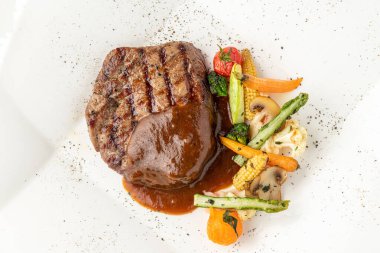 Beyaz porselen tabakta ızgara sebzeli Demi glace soslu ızgara sığır filetosu.
