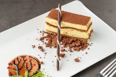 Tiramisu beyaz bir porselen tabakta çikolatayla servis edilir.