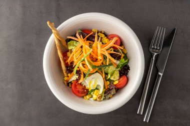 Havuçlu salata, domates, mısır ve beyaz porselen tabakta bir sürü yeşillik.