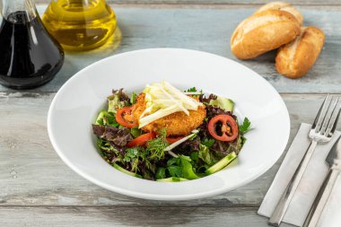 Beyaz porselen tabakta kızarmış keçi peynirli salata.