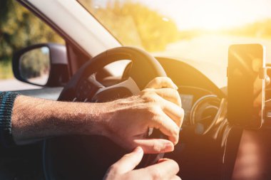 Gün batımında direksiyonda iki eli olan bir adam.