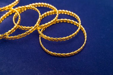 24k (24 karat) Türk altın bileziği altın mağazasının koyu mavi arka planında bir yığın üzerinde duruyor