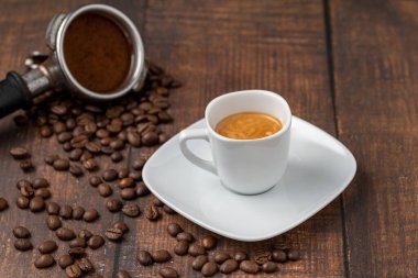Taze espresso kahvesi, ahşap masada kahve çekirdekleri ile süslenmiş.
