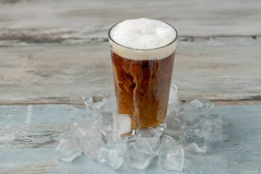 Ahşap masada cam bardakta buzlu kahve.