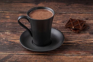 Yanında çikolata olan siyah bir porselen bardakta sıcak çikolata.