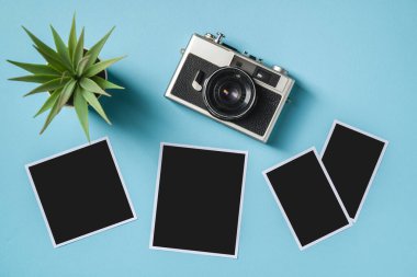 Klasik fotoğraf makinesi ve mavi arkaplanda boş fotoğraf çerçeveleri. Seyahat anı konsepti