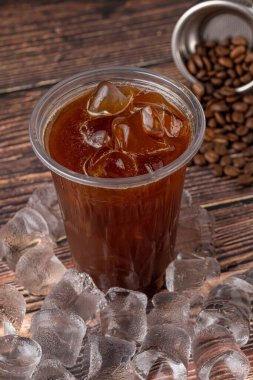 Kahve dükkanındaki ahşap bir masaya buz küplü buzlu Americano kahvesi. Bir bardak kahvenin üst görüntüsü..