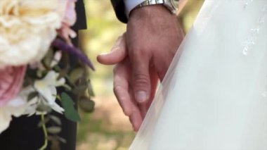 Gelin ve damat güneşli bir günde el ele tutuşuyorlar. Sevgililer Günü konsepti