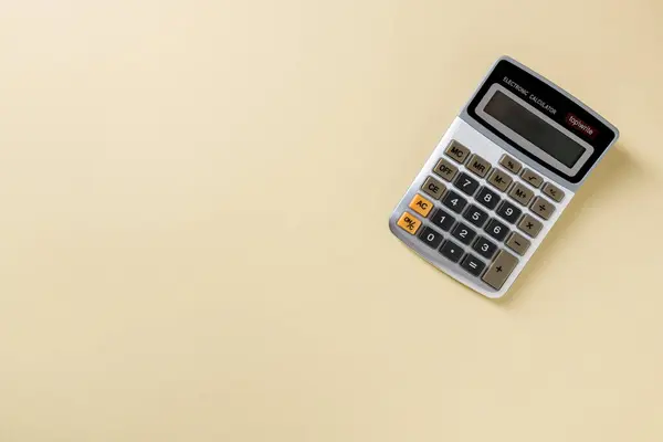 Top view of electronic calculator on yellow background