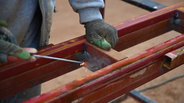 在阳光灿烂的日子里 焊机在建筑工地焊接了两块铁面 — 图库视频影像