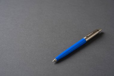 Koyu gri arka planda mavi plastik ve metal tükenmez kalem