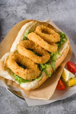 Yanında yeşillik ve ekmeğin içinde kızarmış kalamar. Kalamar sandviçi