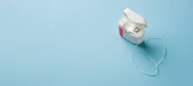 Mavi arkaplanda beyaz kutuda diş ipinin üst görünümü