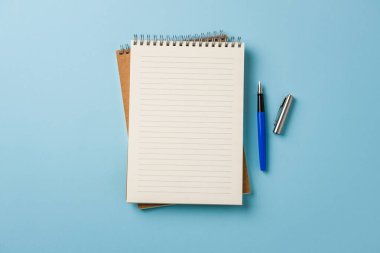 Mavi arkaplanda dizüstü bilgisayar ve dolmakalem görünümü