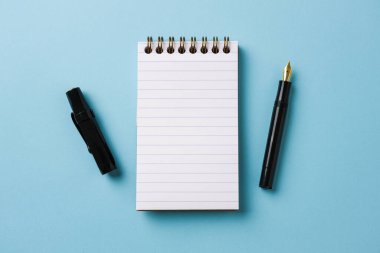 Mavi arkaplanda dizüstü bilgisayar ve dolmakalem görünümü