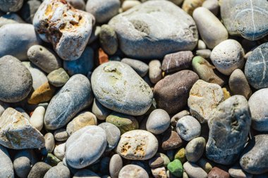 Kumsalda güneşli bir günde küçük yuvarlak taşlar