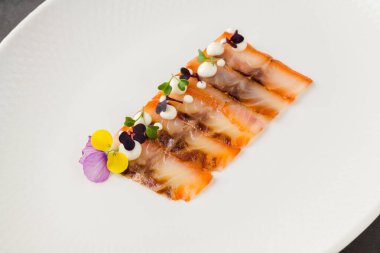 Füme balık pastırması ya da beyaz porselen tabakta domuz pastırması.