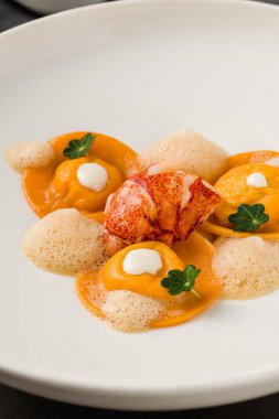 Beyaz porselen tabakta ızgara karidesli Ravioli.