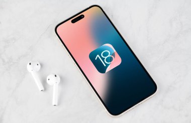 Antalya, Türkiye - 11 Haziran 2024: iPhone 15 Pro ekran ve yeni iOS 18 logosu, Apple 'ın akıllı telefonları için bir sonraki işletim sistemi piyasaya sürülecek