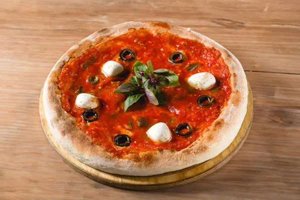 Domatesli Napoli pizzası, mozarella, fesleğen ve mermer masada zeytin.