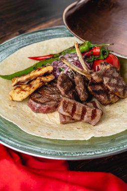 Ahşap masada adana kebabı, ızgara tavuk ve kuzu tandırından oluşan karışık Türk ızgarası.