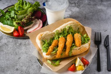 Yanında yeşillik ve ekmeğin içinde kızartılmış karides. Karidesli sandviç.