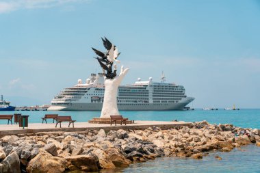 Aydın Kusadasi, Türkiye - 4 Temmuz 2024: Barış Heykeli ve arkasında yolcu gemisi Kusadasi Aydın