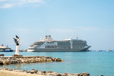Aydın Kusadasi, Türkiye - 4 Temmuz 2024: Barış Heykeli ve arkasında yolcu gemisi Kusadasi Aydın