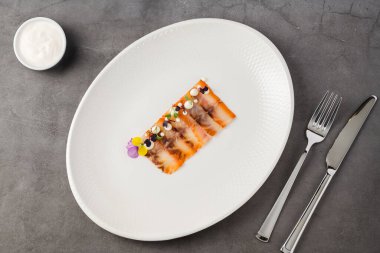 Füme balık pastırması ya da beyaz porselen tabakta domuz pastırması.