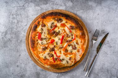 Kırmızı biberli pizza ve taştan masanın üzerinde biftek.