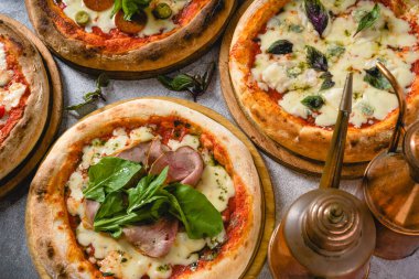 Gri taş masadaki çeşitli Napoli pizzalarının üst görüntüsü