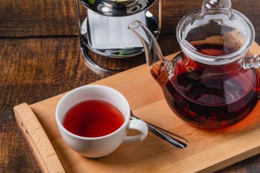 Kırmızı otlardan demlenmiş sağlıklı bitki çayı ve beyaz porselen bir fincanda meyveler.