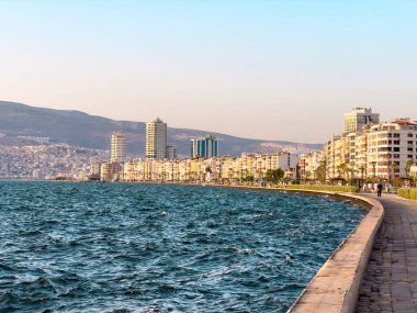 İzmir, Türkiye - 3 Temmuz 2024: İzmir Pasaport Bölgesi 'nde Kordon Caddesi, feribot iskelesi ve yüksek binaların manzarası