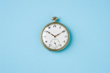 Mavi arkaplandaki antika cep saatinin üst görüntüsü