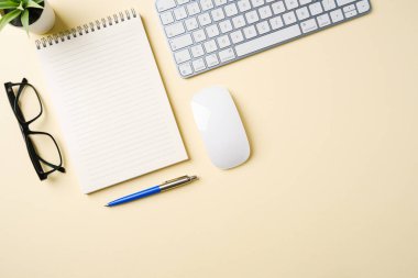 Ofis masasında bilgisayar klavyesi, fare, gözlük, defter ve kalem var. Kopyalama alanı olan üst görünüm. Düz yatıyordu